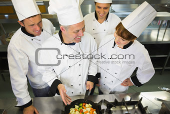 Experienced head chef showing pan to his colleagues