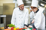 Female chef slicing vegetables with colleague