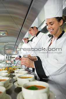 Smiling chef seasoning her soup