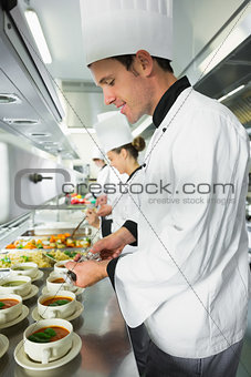 Smiling handsome chef seasoning his soup