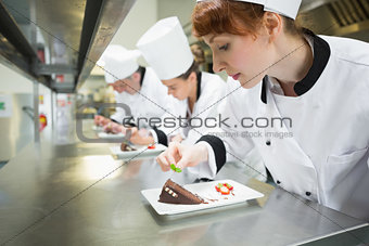 Chefs standing in a row garnishing dessert plates