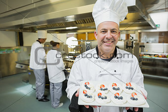 Smiling chef presenting proudly plate of meringues