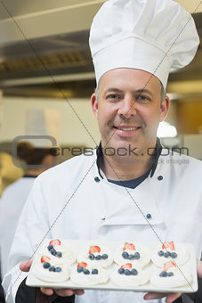 Happy chef presenting plate of meringues