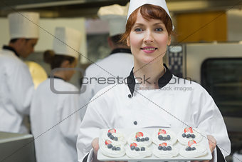 Happy female chef presenting plate of meringues