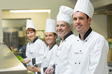 Four chefs working in a kitchen standing in a row
