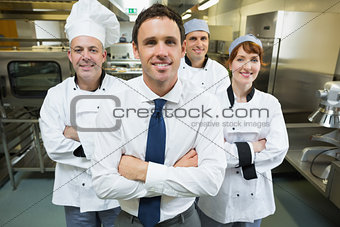 Restaurant manager posing in front of team of chefs