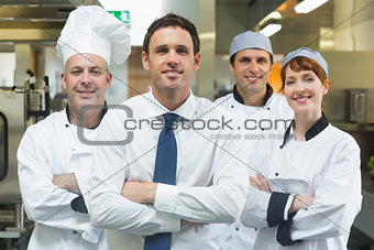Restaurant manager standing in front of team of chefs