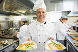 Mature head chef presenting proudly some dinner plates
