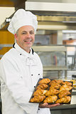 Baker showing some croissants on a baking tray