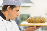 Young baker inspecting a seeded loaf of bread