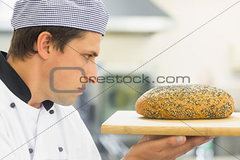 Young baker inspecting a seeded loaf of bread