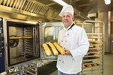 Mature baker showing three baguettes