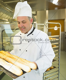Mature head chef holding some baguettes