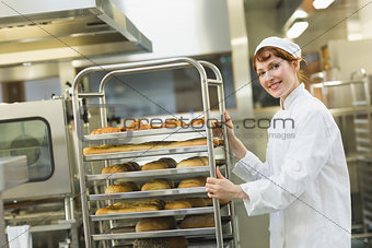Pretty young female baker pushing a trolley
