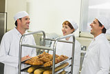 Three young chatting bakers standing in a kitchen