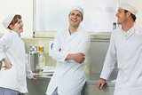 Three chatting bakers standing in a bakery