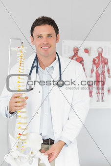 Handsome smiling doctor holding skeleton model