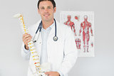 Handsome content doctor holding skeleton model