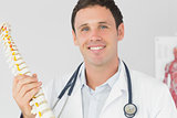 Handsome happy doctor holding skeleton model