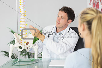 Content doctor showing a patient something on skeleton model