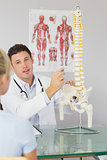 Attractive doctor showing a patient something on skeleton model