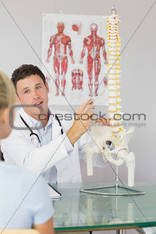 Attractive doctor showing a patient something on skeleton model