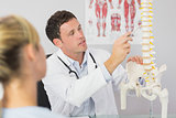 Good looking doctor showing a patient something on skeleton model