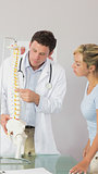 Serious doctor showing a patient something on skeleton model