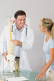Cheerful doctor showing a patient something on skeleton model