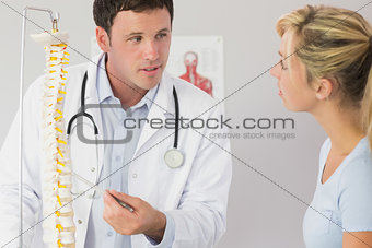 Nice looking doctor showing a patient something on skeleton model