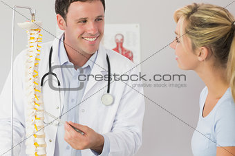 Lucky doctor showing a patient something on skeleton model