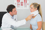Attractive doctor examining neck of a patient