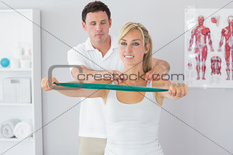 Handsome physiotherapist correcting position of patient