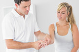 Pleased physiotherapist examining patients hand