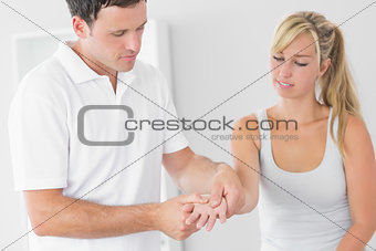 Pleased physiotherapist examining patients hand