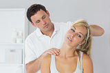 Handsome physiotherapist examining patients neck