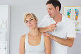 Attractive physiotherapist massaging patients neck with elbow