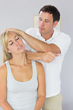 Handsome physiotherapist massaging patients neck with elbow