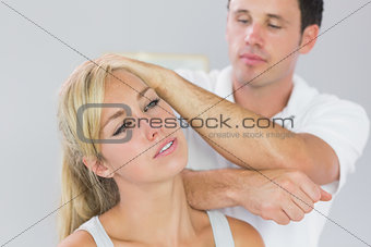 Good looking physiotherapist massaging patients neck with elbow
