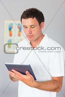 Handsome physiotherapist using tablet