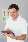 Handsome smiling physiotherapist using tablet