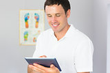 Handsome cheerful physiotherapist using tablet