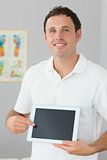 Handsome cheerful physiotherapist showing tablet