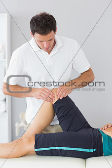 Physiotherapist examining knee of a patient