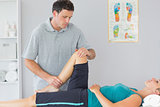 Attractive physiotherapist controlling knee of a patient