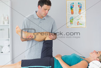 Good looking physiotherapist controlling knee of a patient
