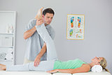 Handsome physiotherapist stretching patients leg
