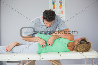Handsome physiotherapist manipulating patients back