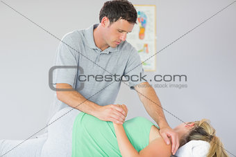 Handsome physiotherapist manipulating patients shoulder
