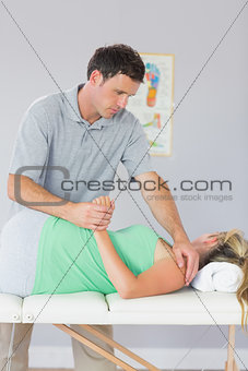 Handsome physiotherapist manipulating patients arm behind back